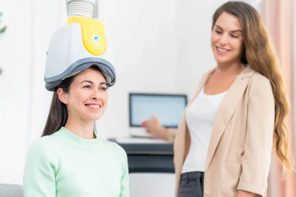 Person wearing a BrainsWay Deep TMS helmet with provider nearby
