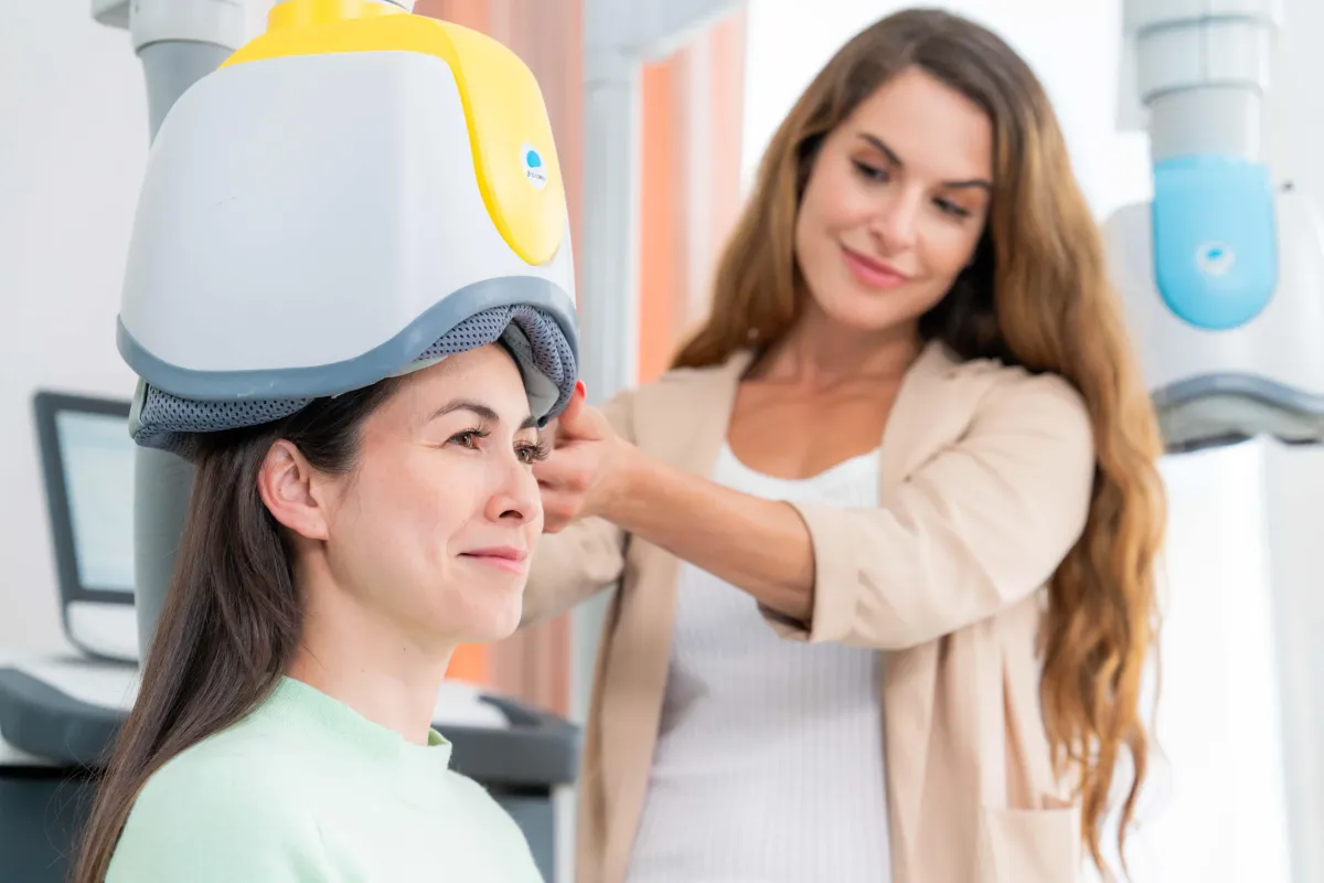 Provider adjusting a BrainsWay Deep TMS helmet on a seated person